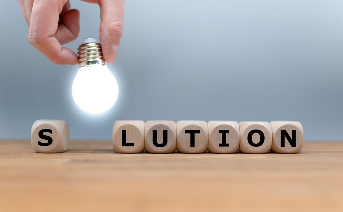 The word solution spelled out with letters on wooden blocks, the first O is a lightbulb
