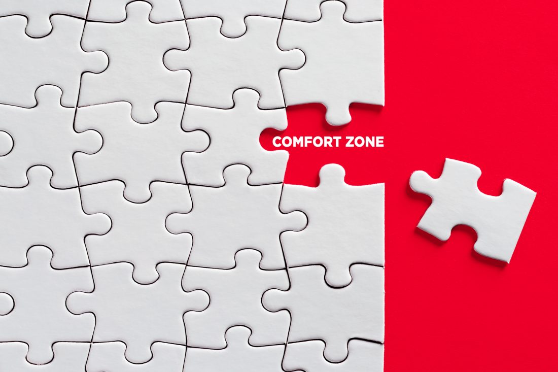 The word comfort zone with missing puzzle piece on red background.